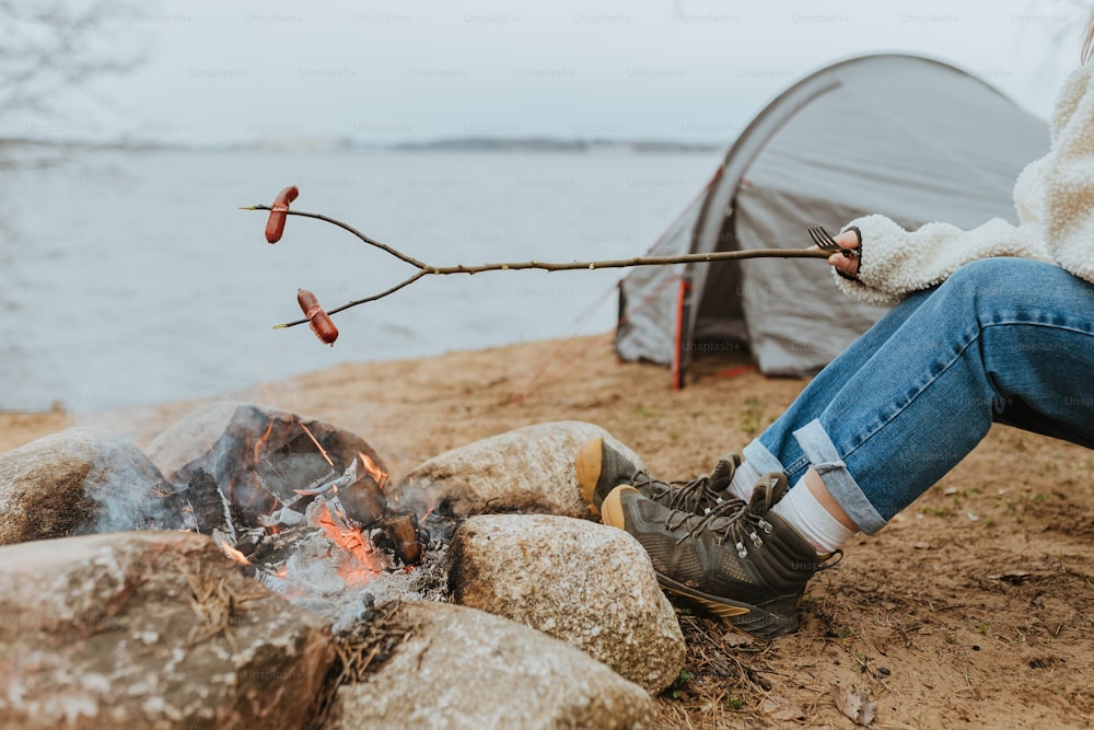 une personne assise près d’un feu de camp près d’une tente