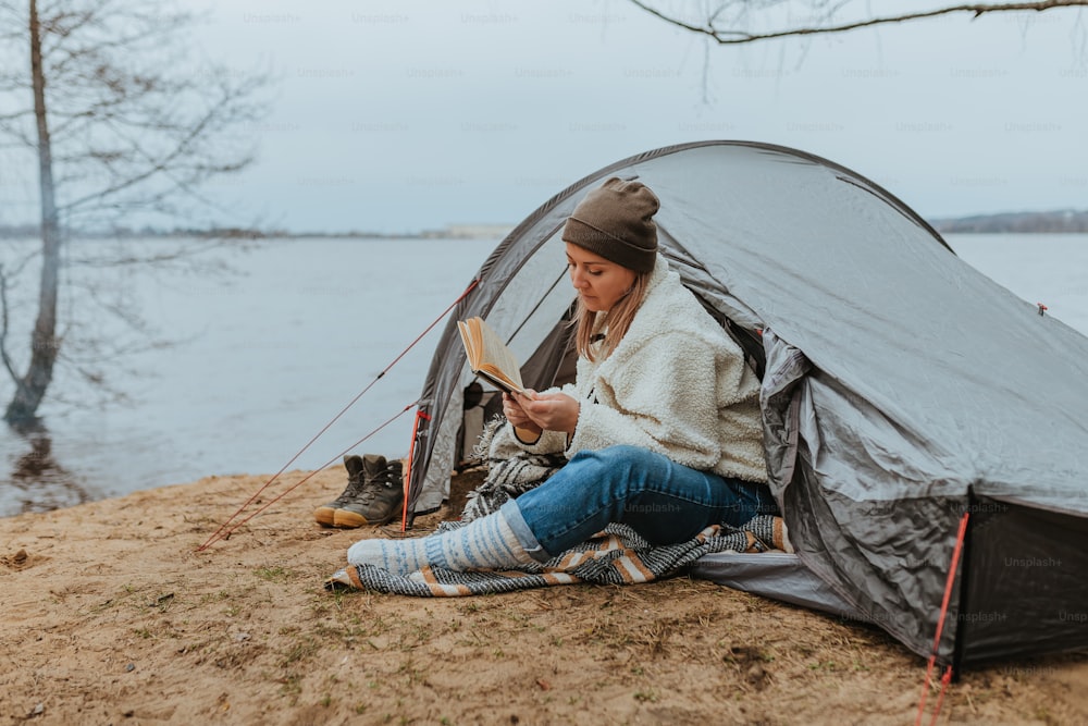 a woman sitting in a tent reading a book