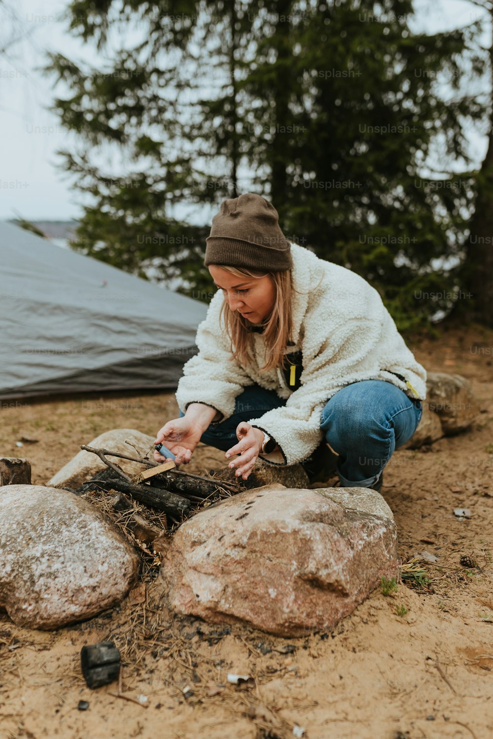 a woman sitting on top of a rock next to a tent