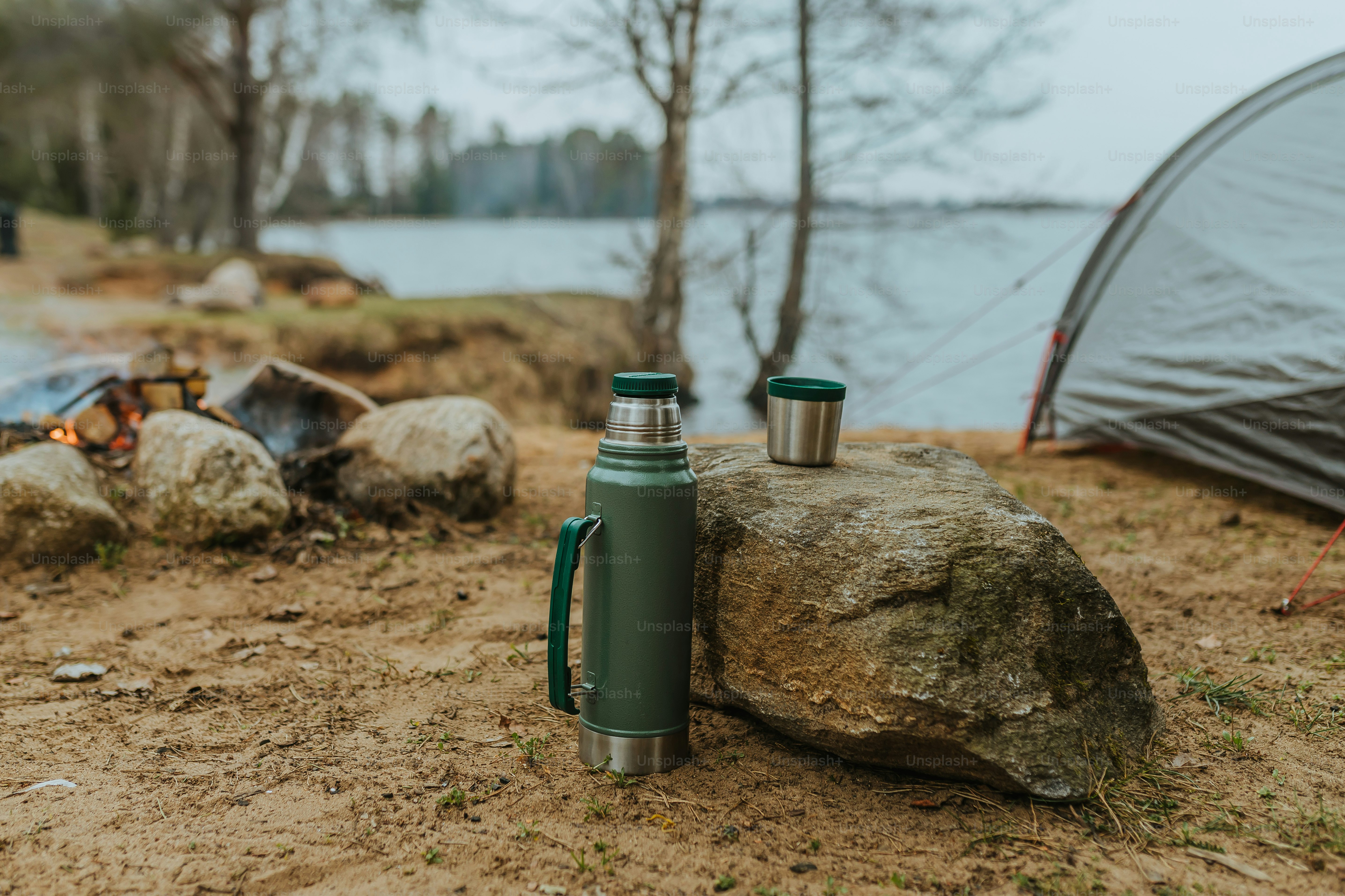a green cup sitting on top of a rock next to a campfire