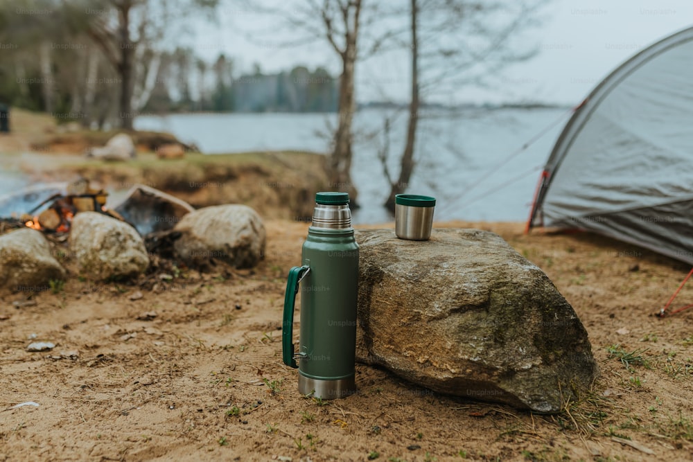 a green cup sitting on top of a rock next to a campfire