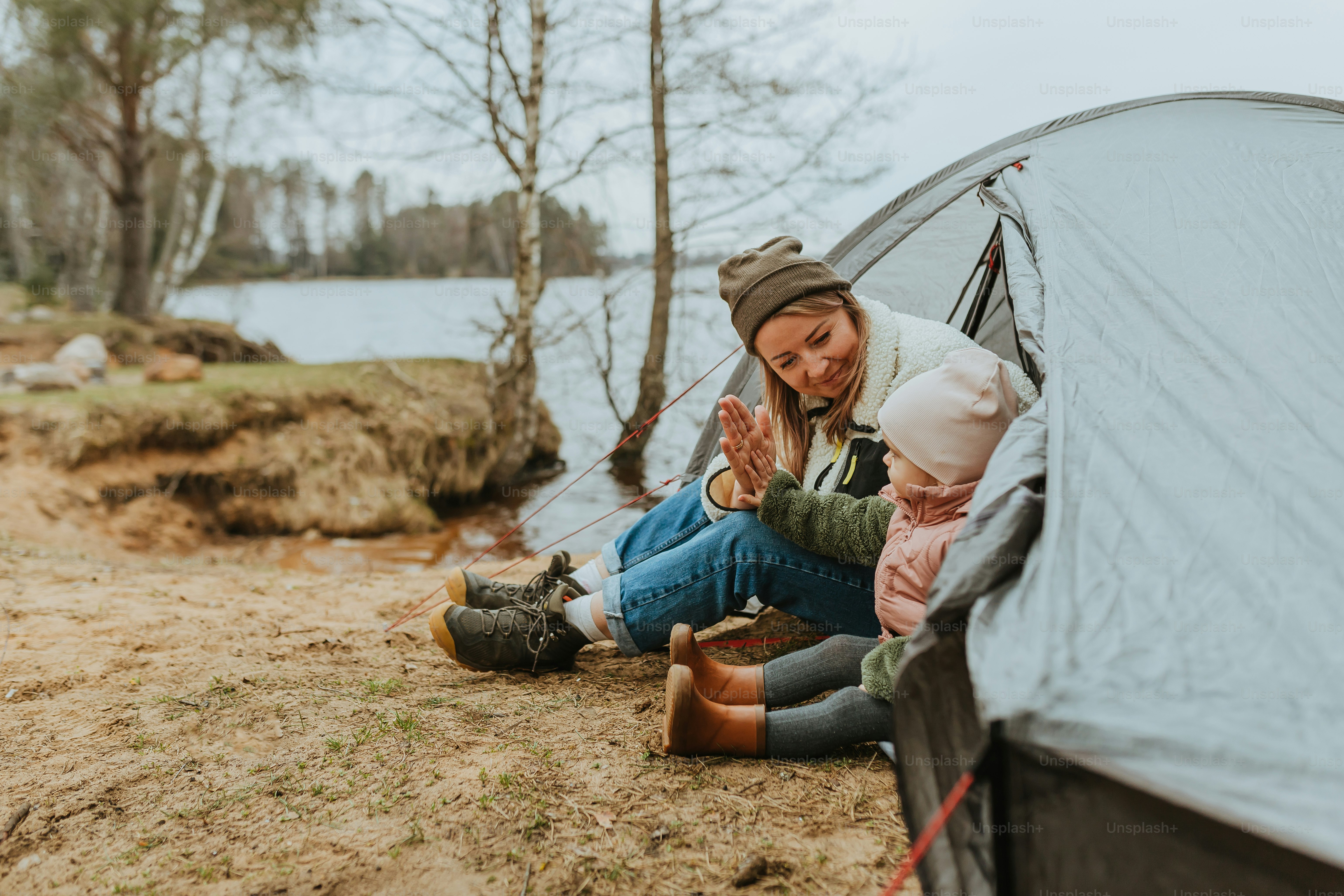 a woman and a child sitting in front of a tent