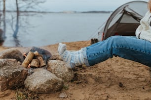 a woman sitting on a rock next to a campfire