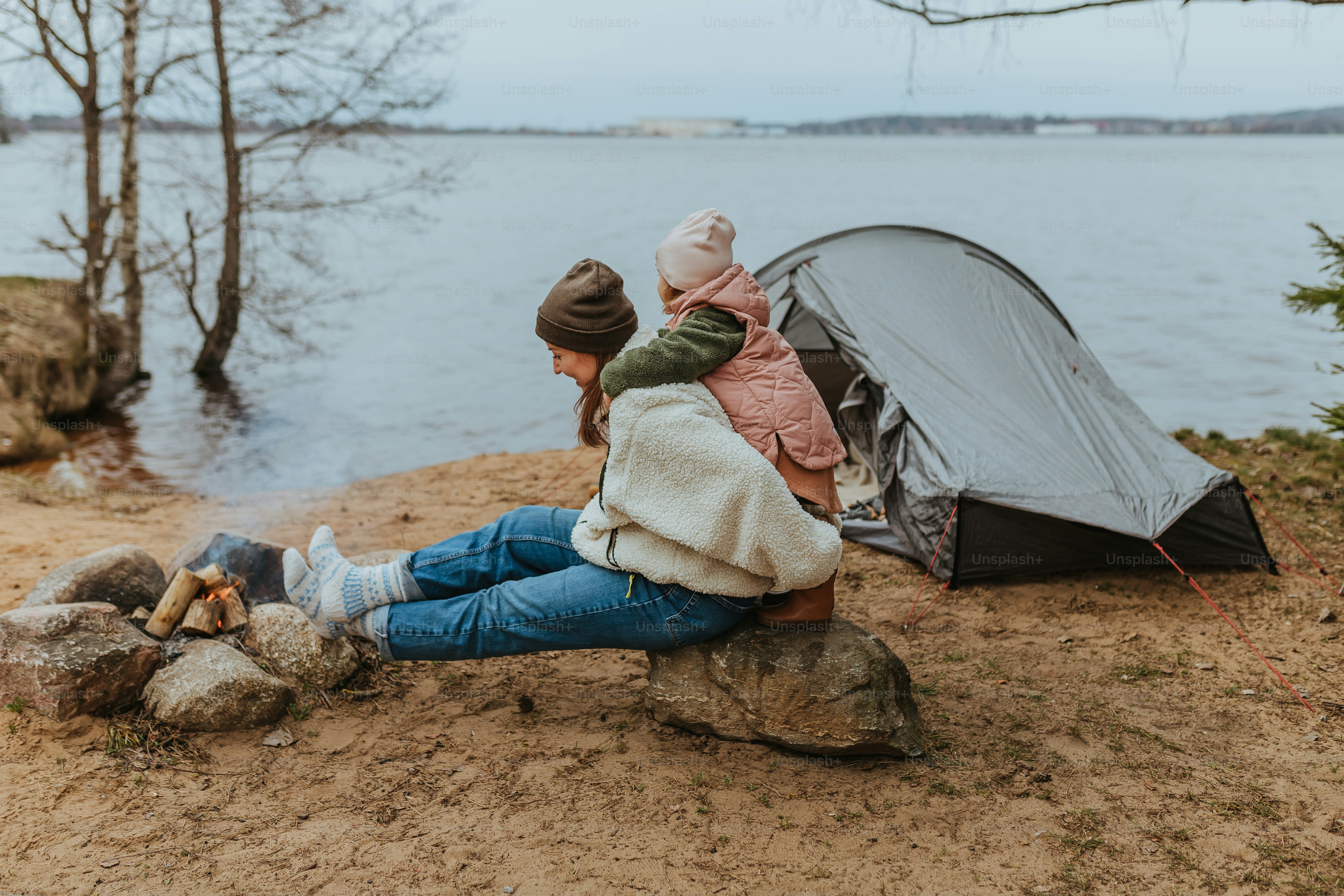a woman sitting on a rock next to a tent