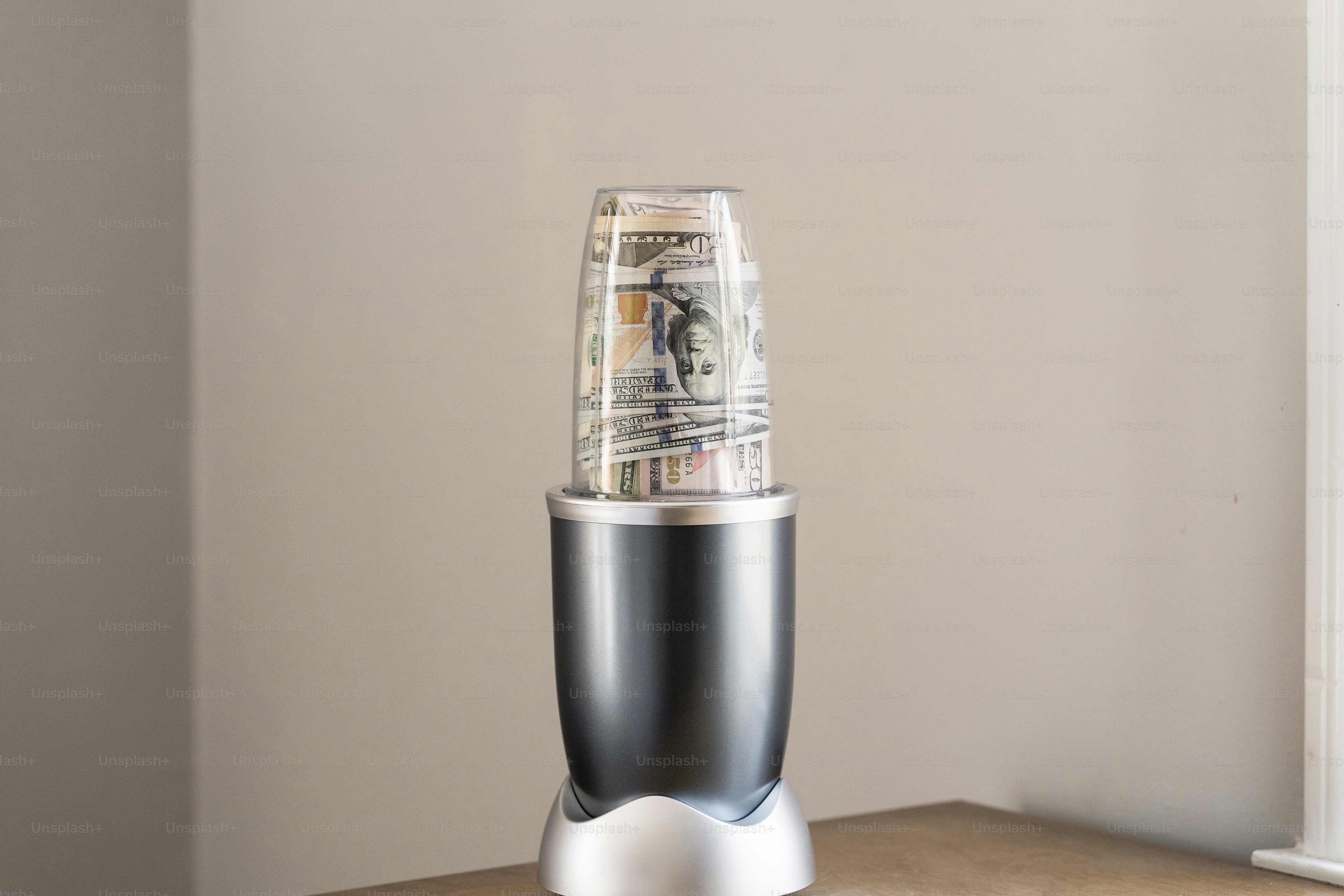 um liquidificador prateado e preto sentado em cima de uma mesa de madeira