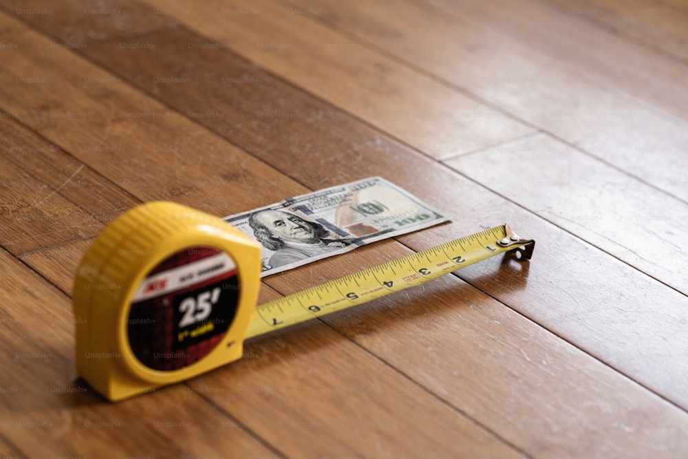 Una cinta métrica y dinero en un piso de madera