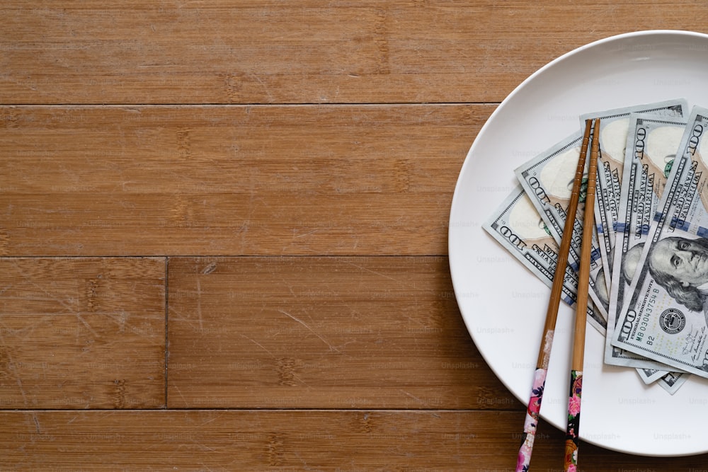 a white plate topped with money and chopsticks