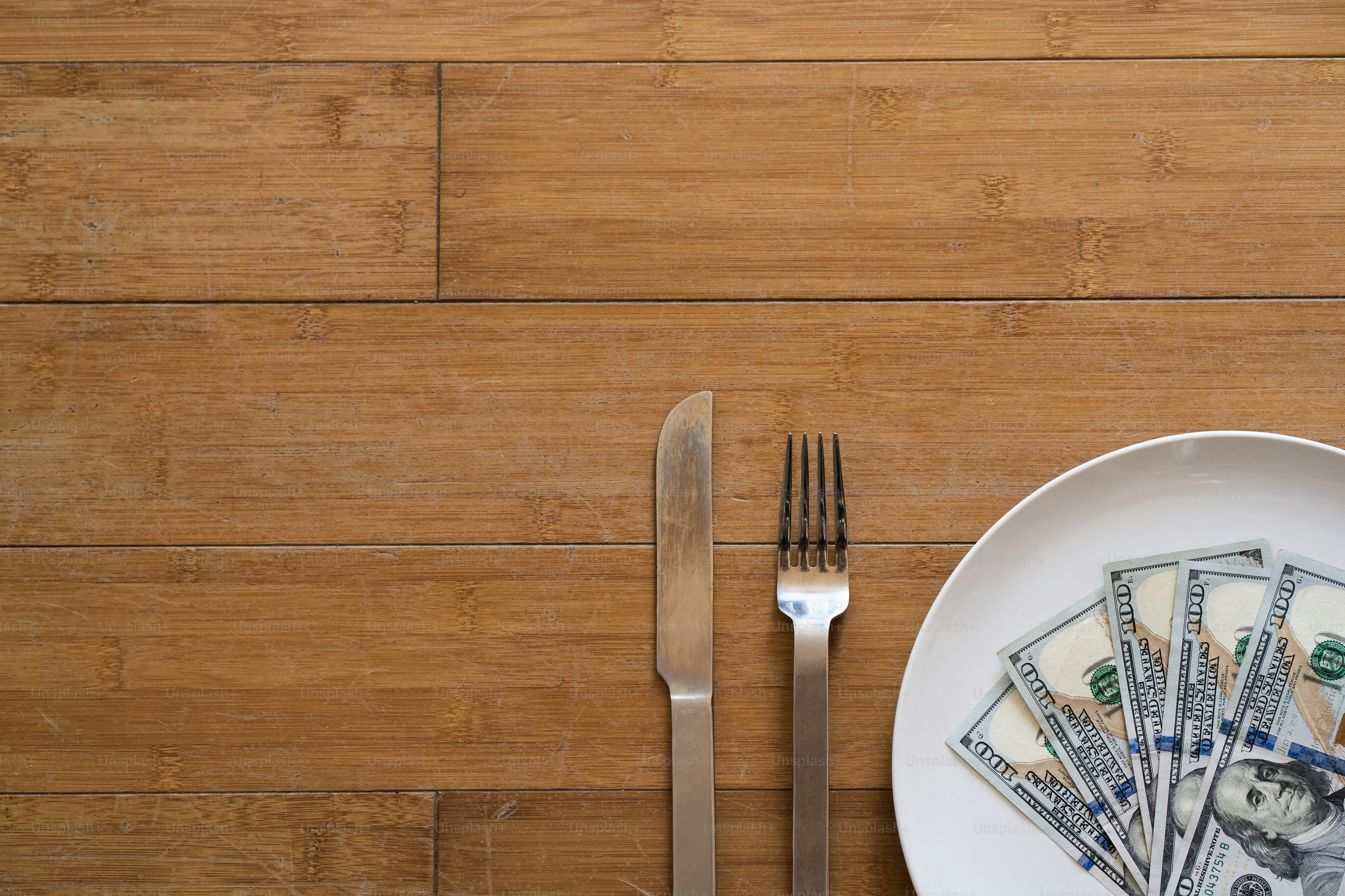 um prato com um garfo, faca e dinheiro sobre ele