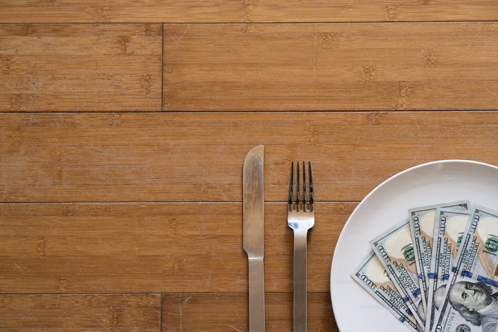 a plate with a fork, knife and money on it