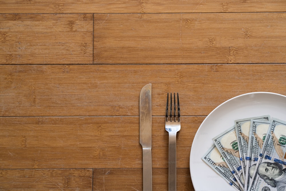 un plato con un tenedor, un cuchillo y dinero