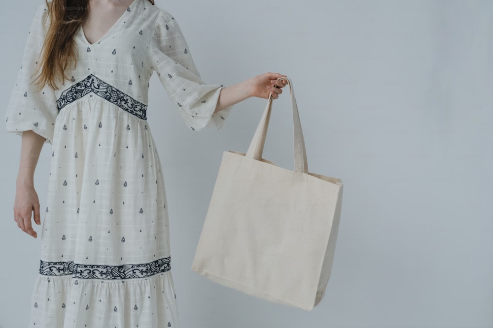 a woman in a white dress holding a beige bag