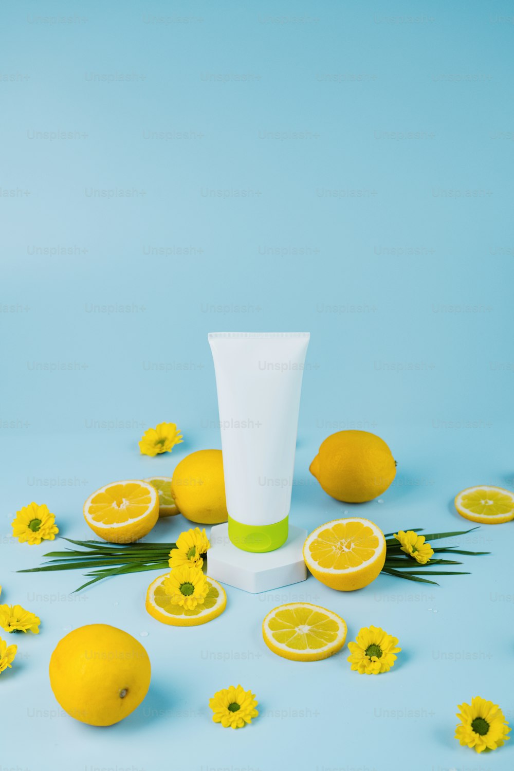 a tube of cream surrounded by lemons and flowers