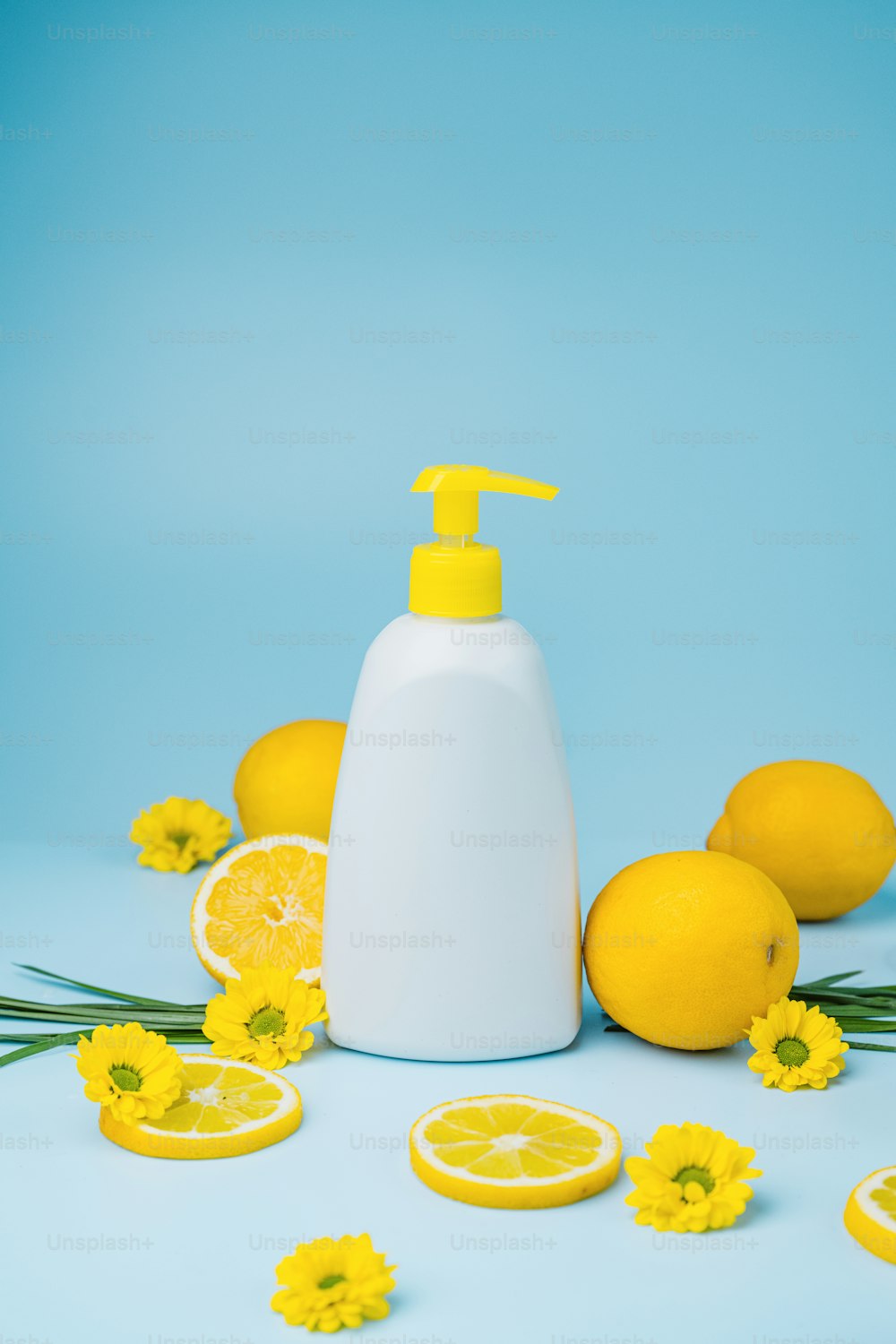 Una botella de jabón rodeada de limones y flores