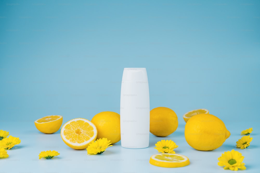 a white bottle surrounded by yellow flowers and lemons