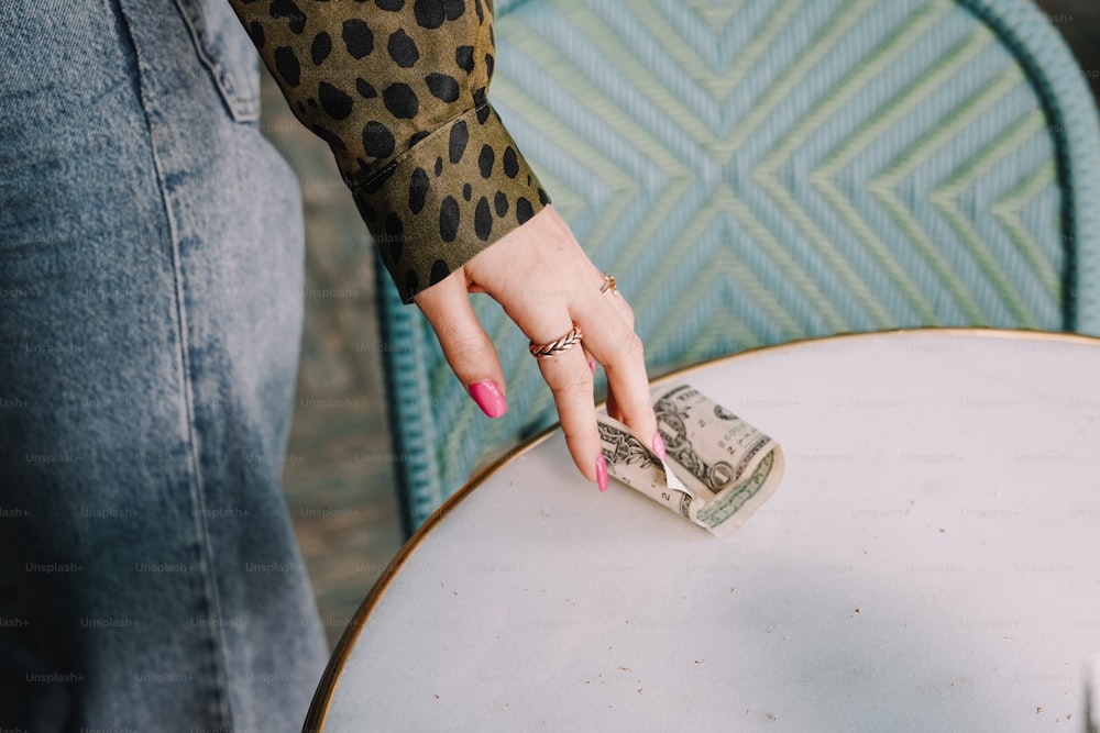 a woman holding a roll of money on top of a table