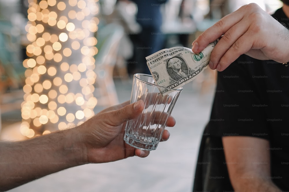 a person handing money to another person holding a glass