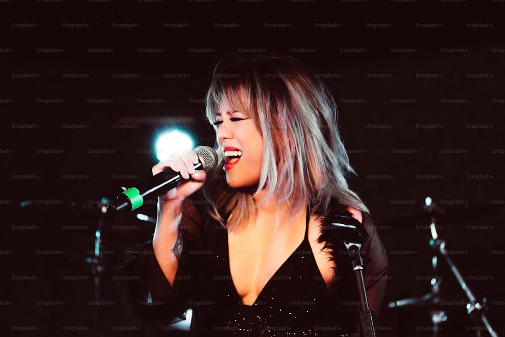 Una donna in un vestito nero che canta in un microfono