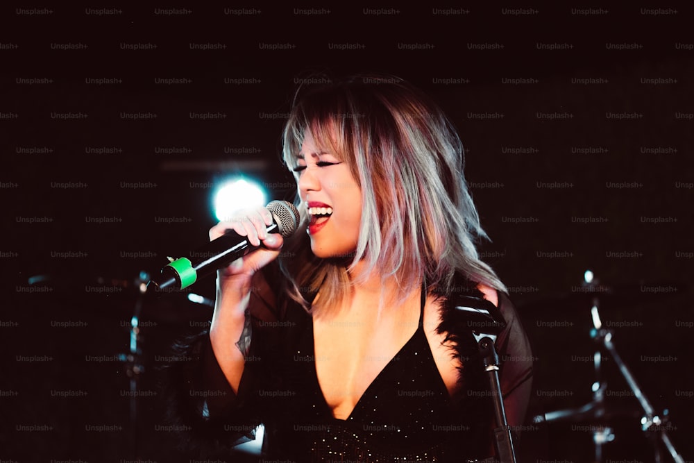 uma mulher em um vestido preto cantando em um microfone
