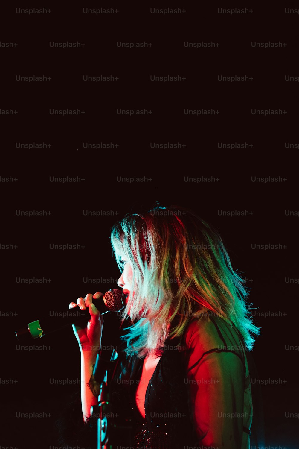 a woman singing into a microphone in a dark room
