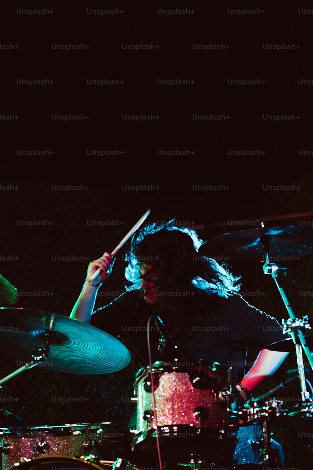 um homem com cabelos compridos tocando bateria em um palco