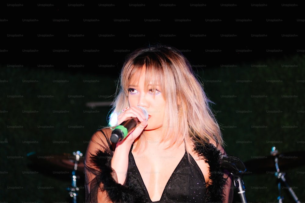 a woman in a black dress singing into a microphone