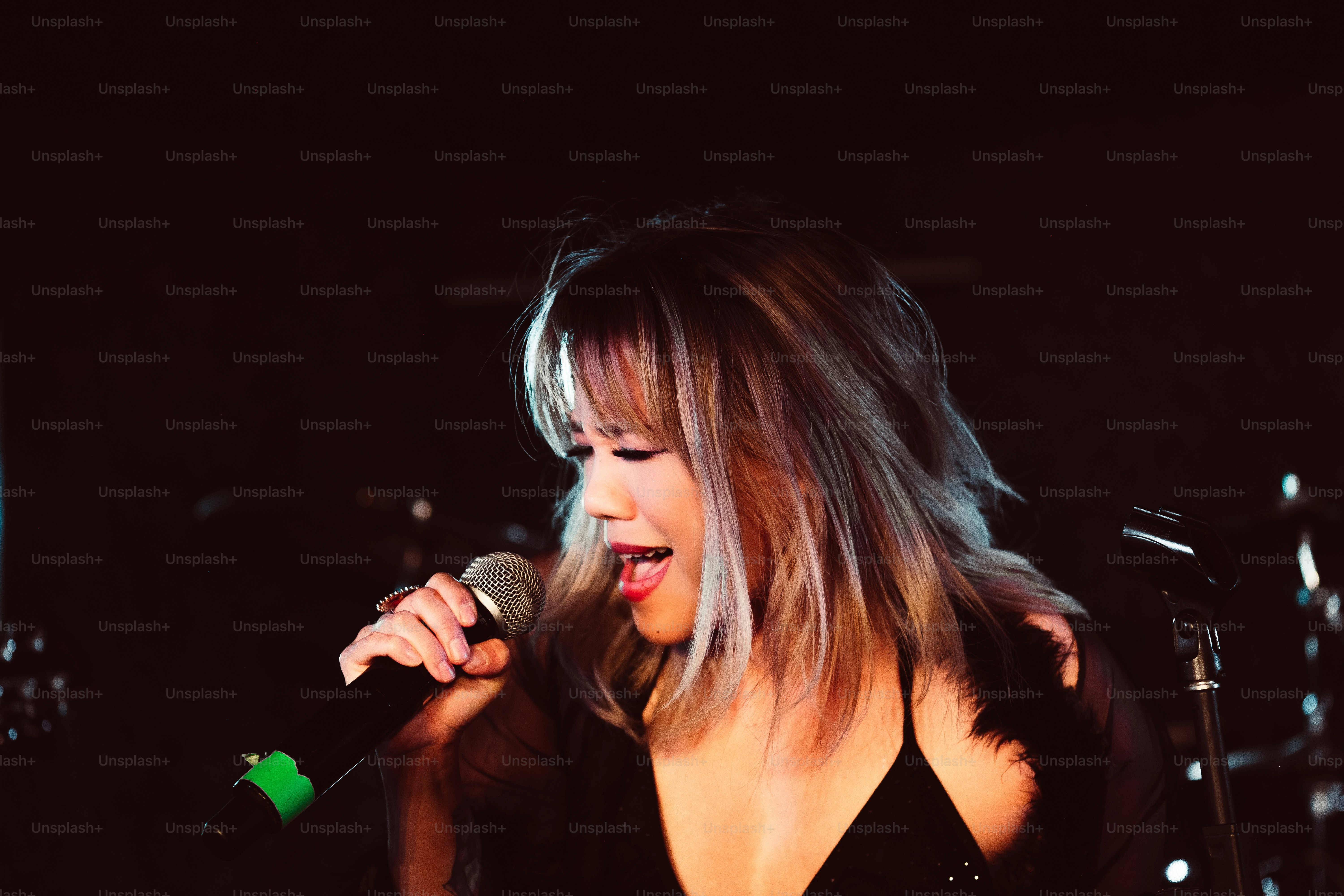 Una mujer cantando en un micrófono en una habitación oscura