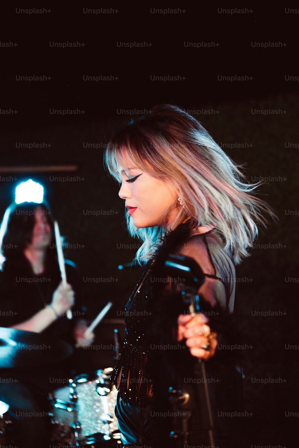 a woman in a leather outfit playing drums