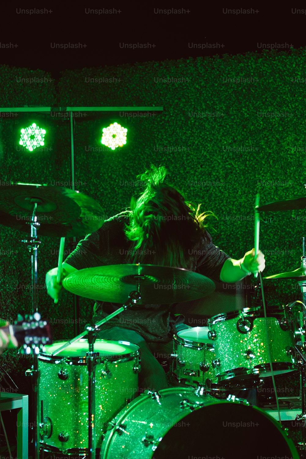 a man with long hair playing drums on a stage