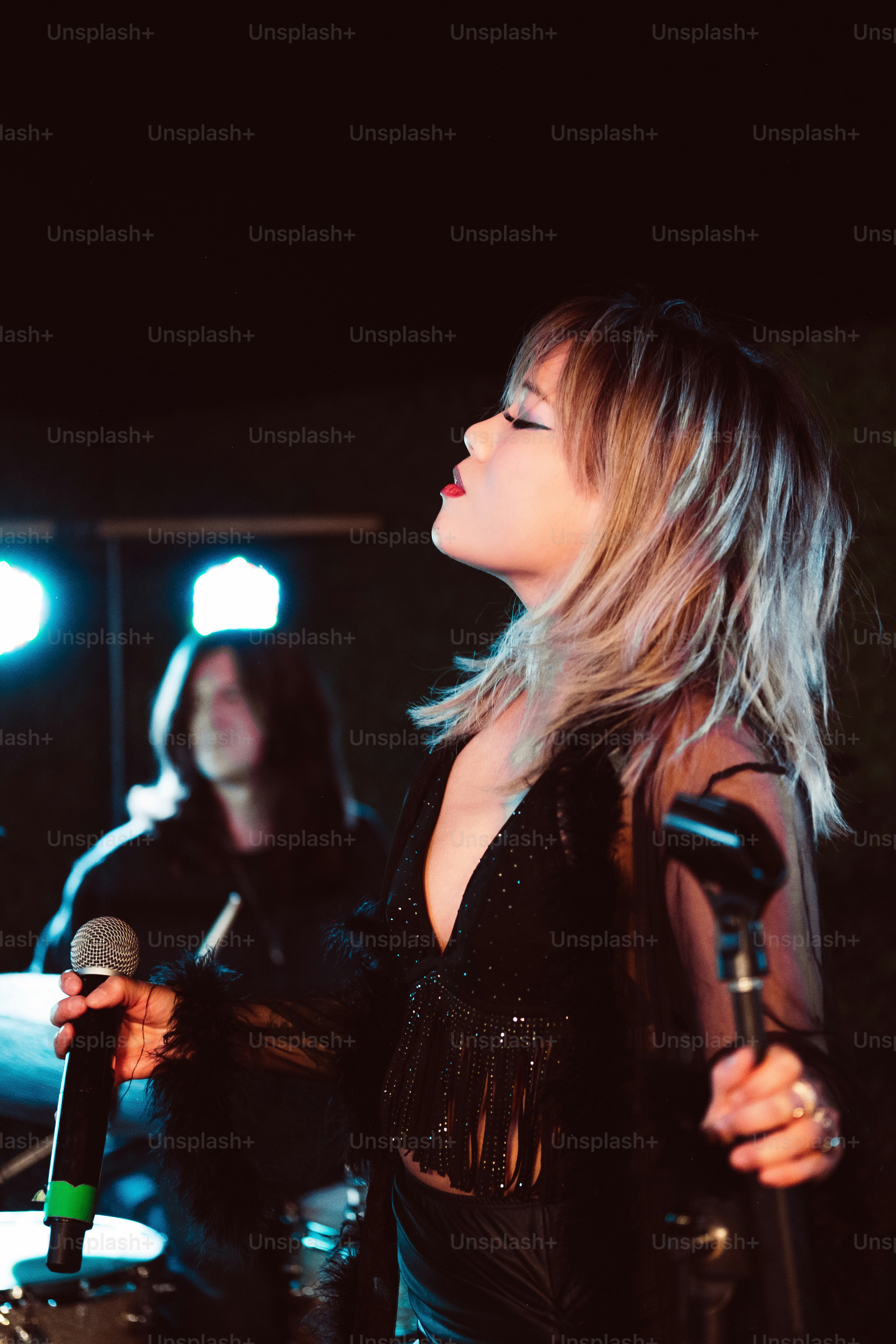 Una mujer con un vestido negro sosteniendo un micrófono