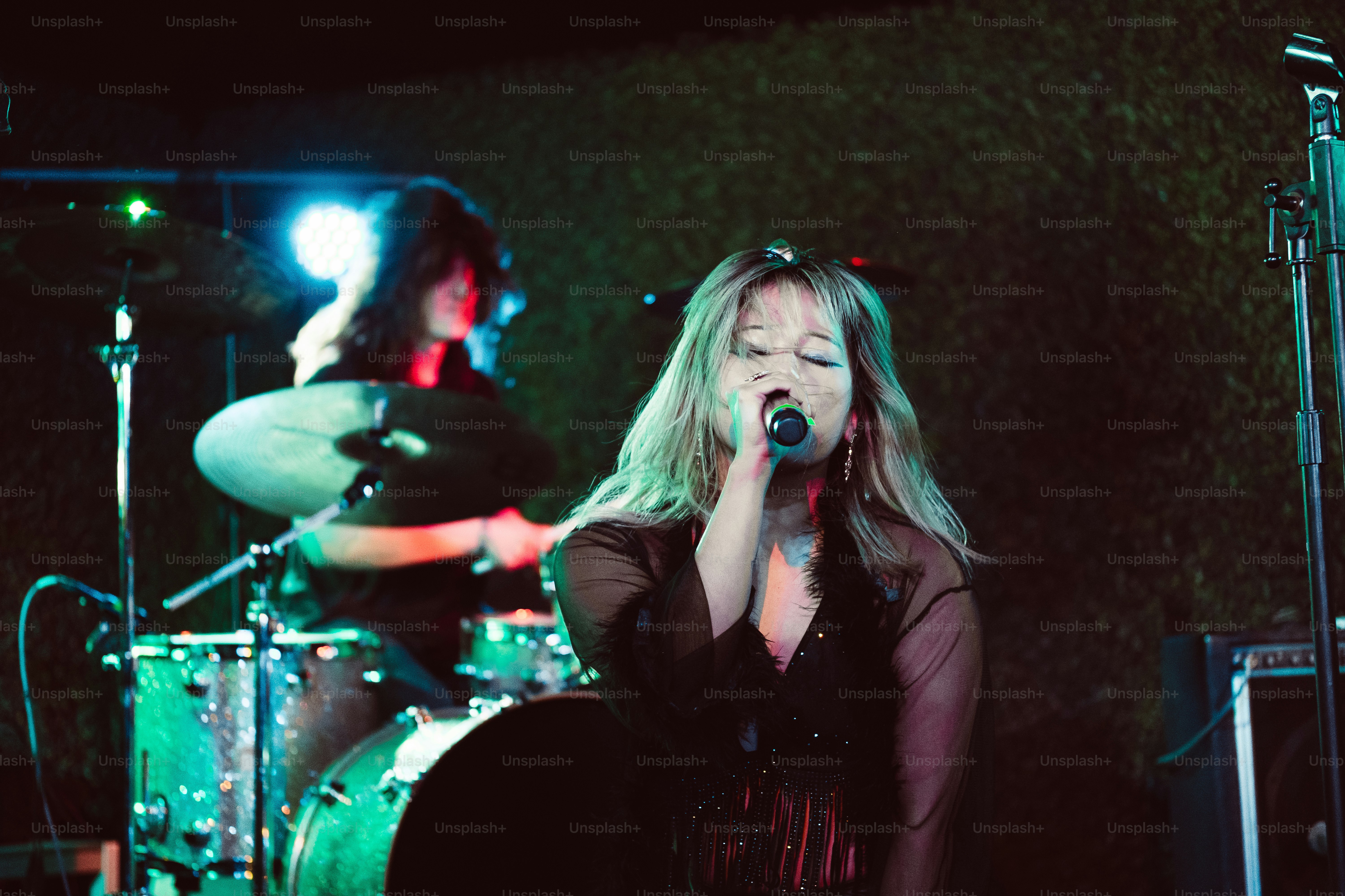Una mujer cantando en un micrófono frente a una banda