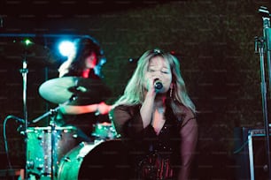 a woman singing into a microphone in front of a band