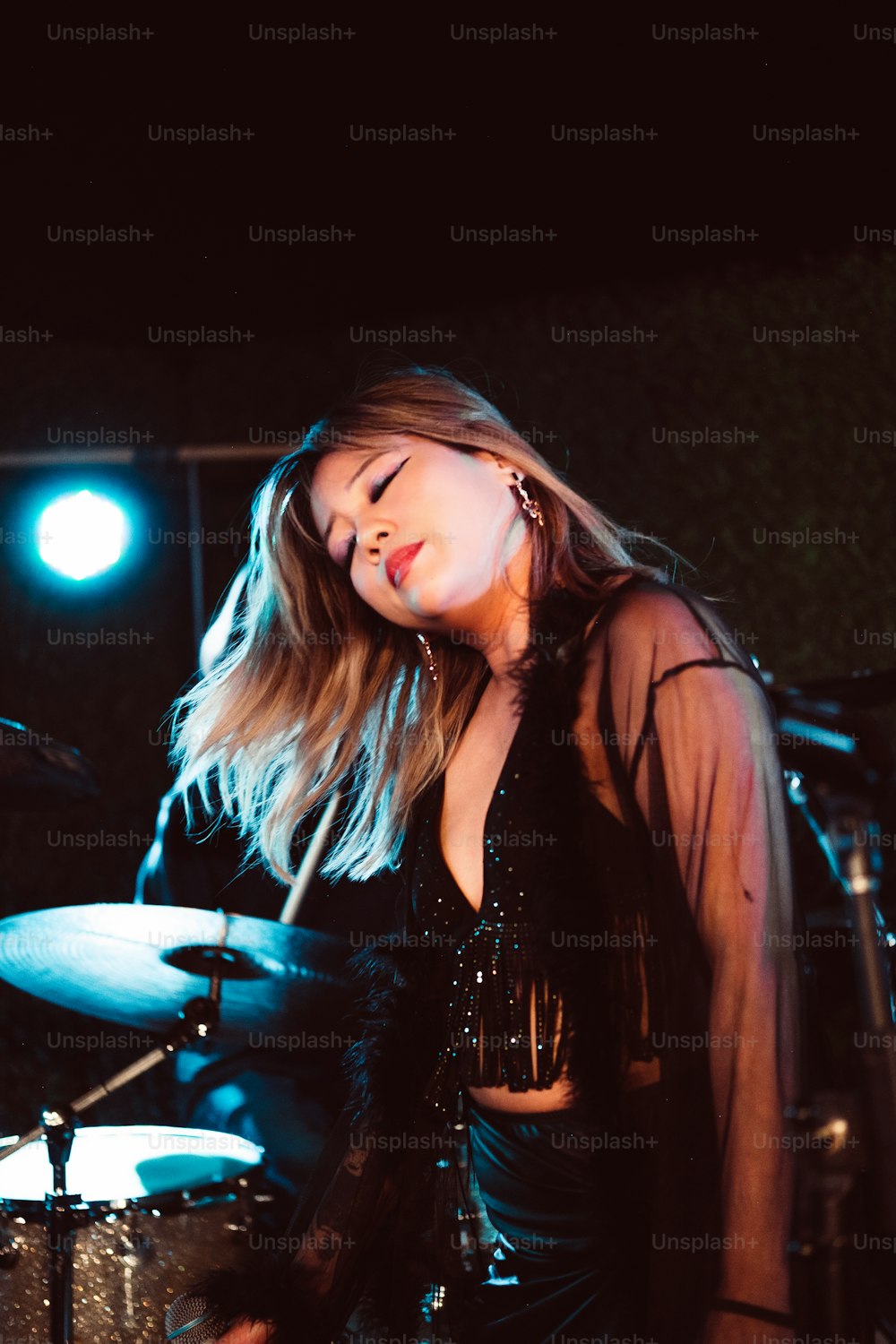 a woman in a black outfit is playing drums