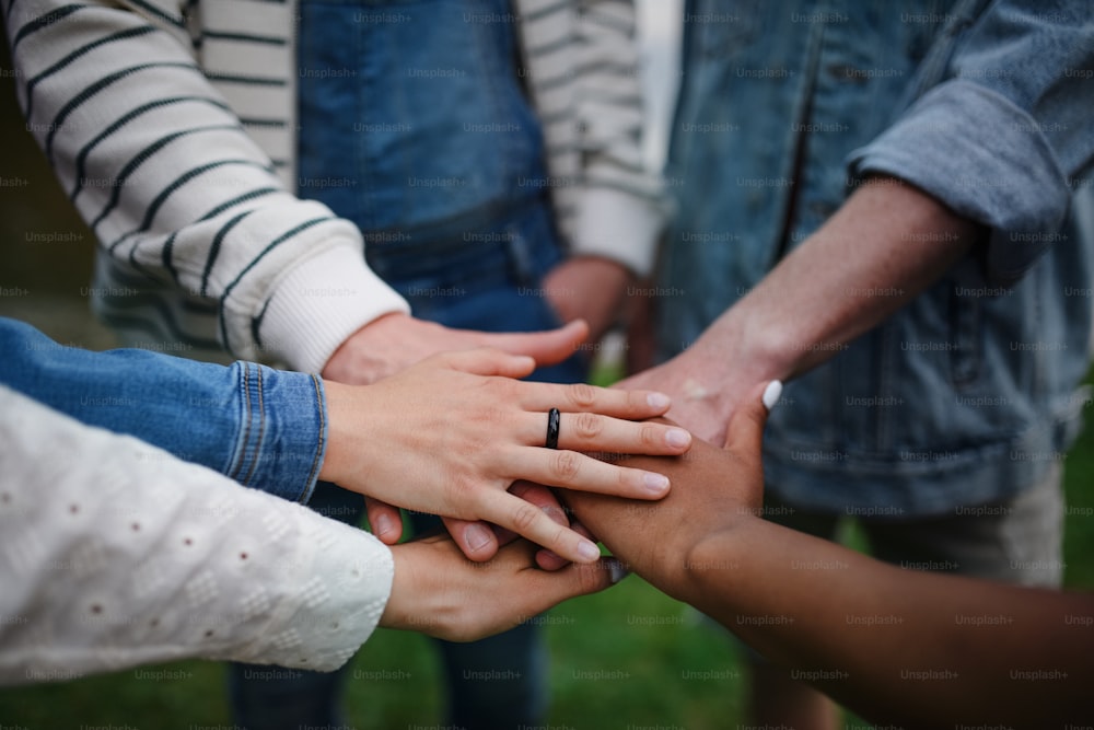 Un primer plano de un grupo diverso de amigos apilando sus manos juntas en círculo, Amistad y conceptos de estilo de vida