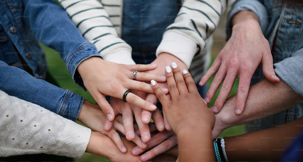 Un primo piano di un gruppo eterogeneo di amici che impilano le mani insieme in cerchio, concetti di amicizia e stile di vita