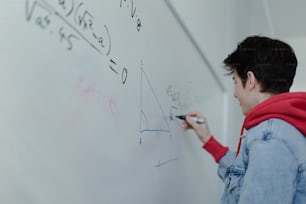 Vue arrière d’un élève du secondaire résolvant un problème mathématique sur un tableau blanc en classe.