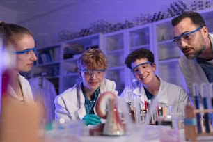 Estudantes de ciências com um professor fazendo experimento de reação química no laboratório da universidade.