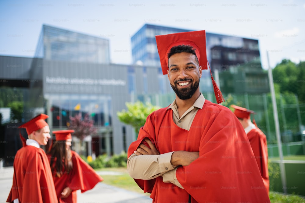 Porträt eines glücklichen Universitätsstudenten mit Hut und Kleid, der im Freien in die Kamera schaut, Abschlusskonzept.