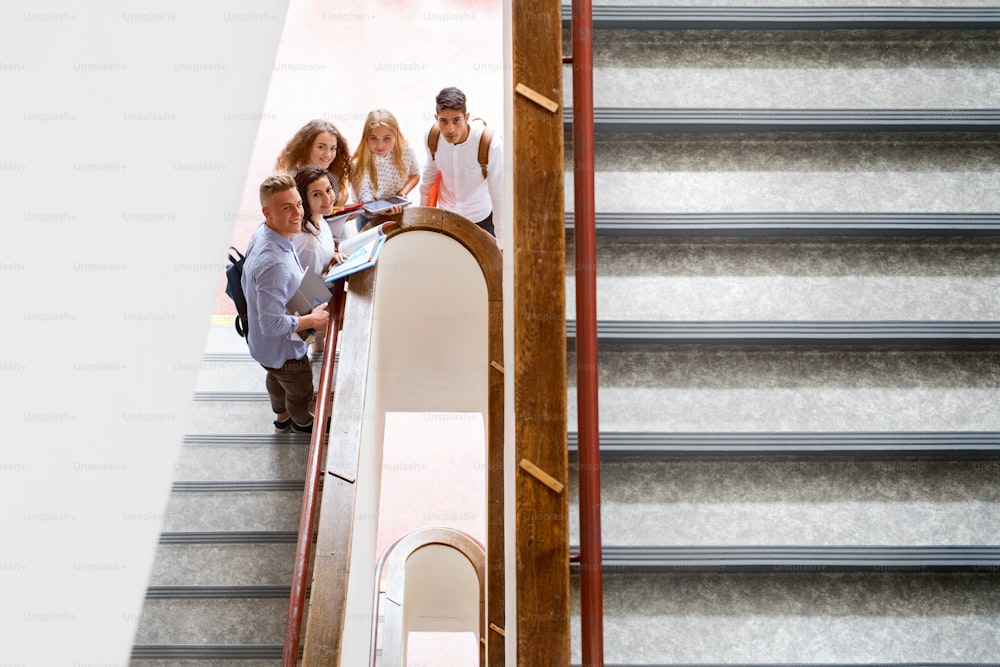 Grupo de estudantes adolescentes atraentes no ensino médio em pé em escadas.