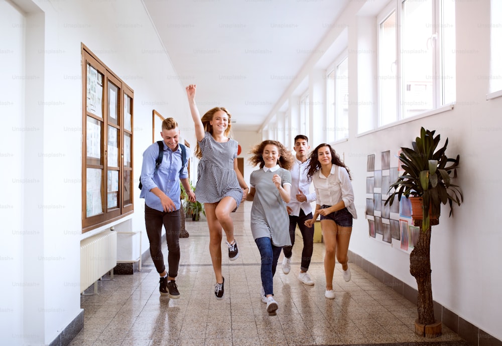 Group attractive teenage students in high school hall jumping high.