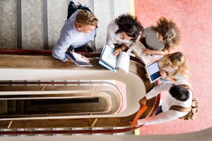 Grupo de estudiantes adolescentes atractivos en la escuela secundaria parados en las escaleras, leyendo libros.