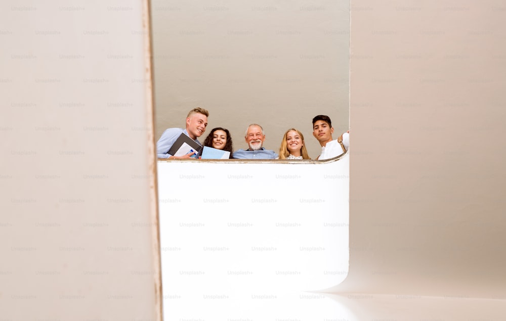 Group of attractive teenage students with their teacher on stairs in high school.