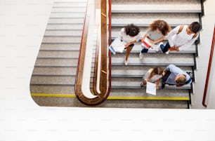 Group of attractive teenage students in high school walking down the stairs.