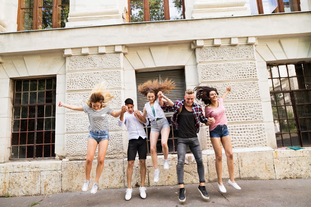 Group attractive teenage students in front of university jumping high.