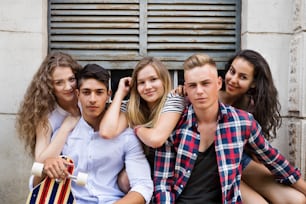 Grupo de estudantes adolescentes atraentes posando em frente à antiga universidade.