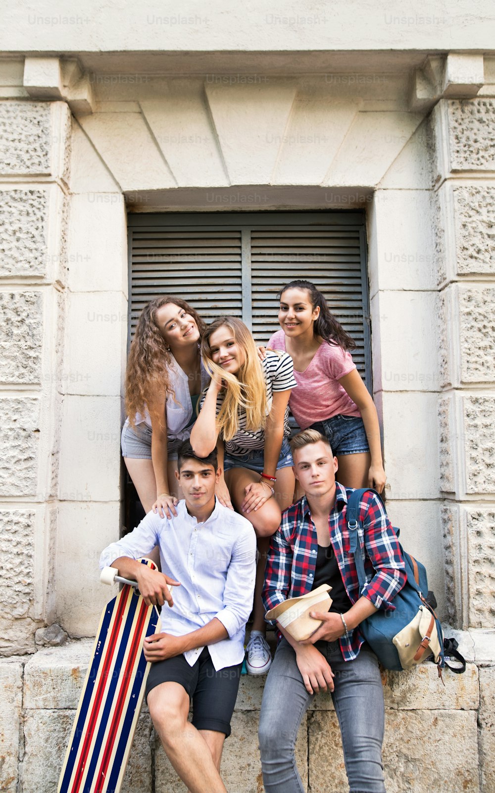 Group of attractive teenage students posing in front of university.