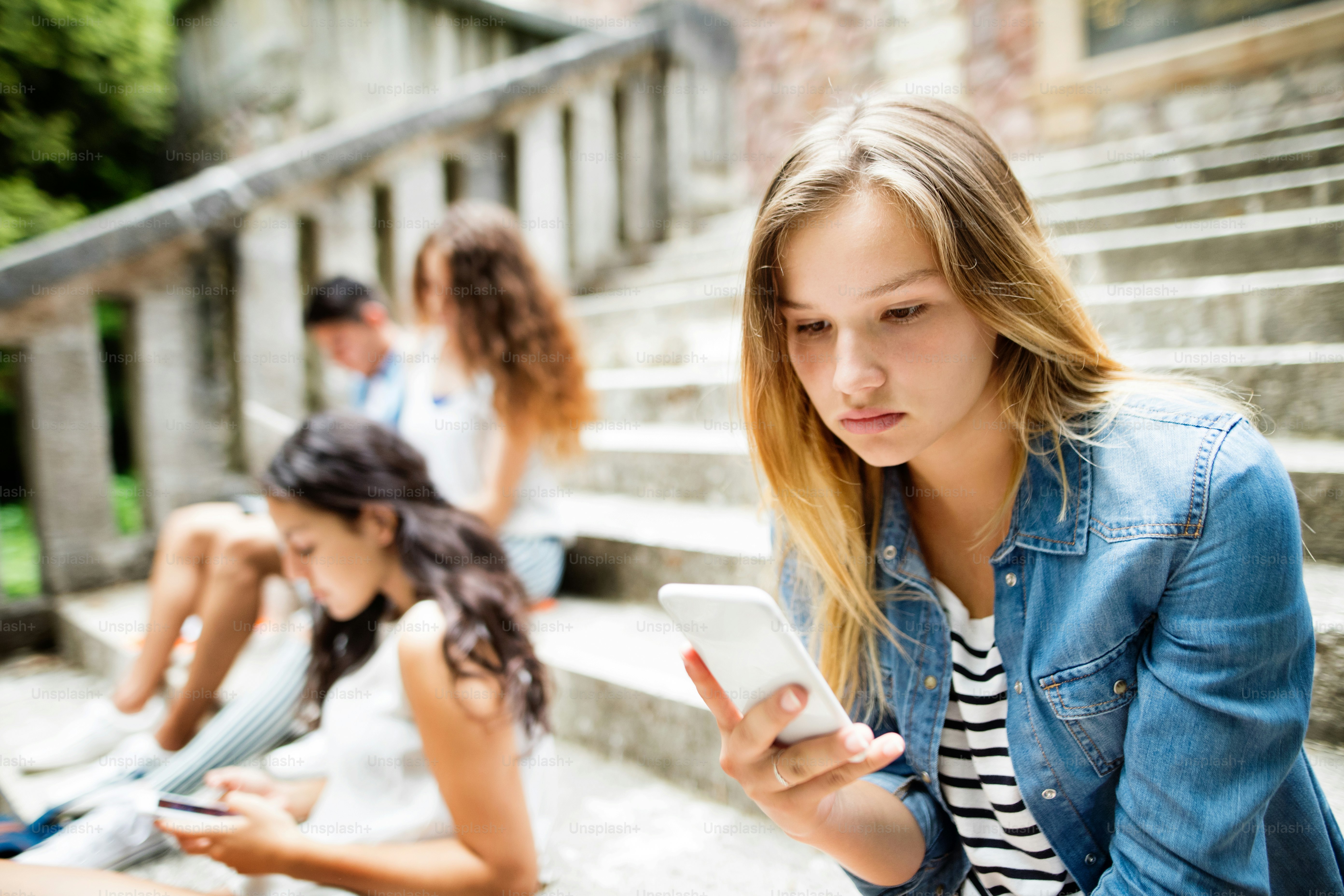 Teen using wellness apps for teen anxiety while sitting on bedroom floor with phone in hand