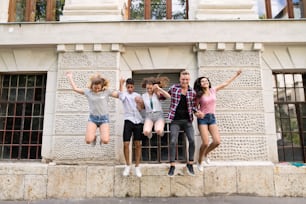 Group attractive teenage students in front of university jumping high.