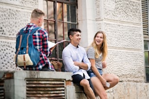 Group of attractive teenage students in front of university studying, talking and laughing together.