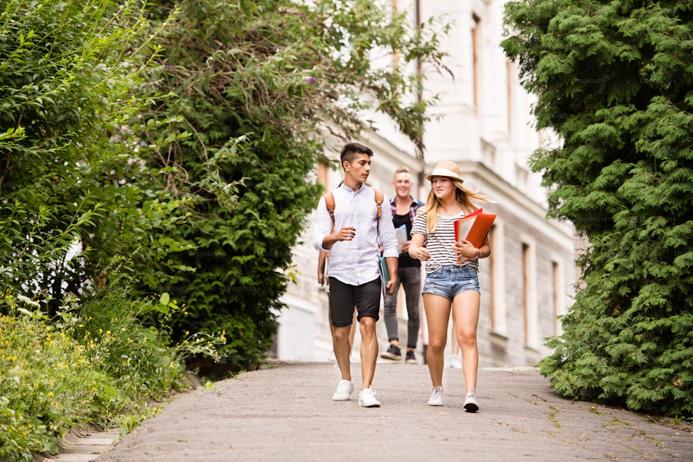 대학에서 걸어 다니는 네 명의 매력적인 십대 학생들.