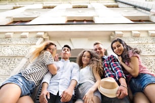 Group of attractive teenage students posing in front of university.